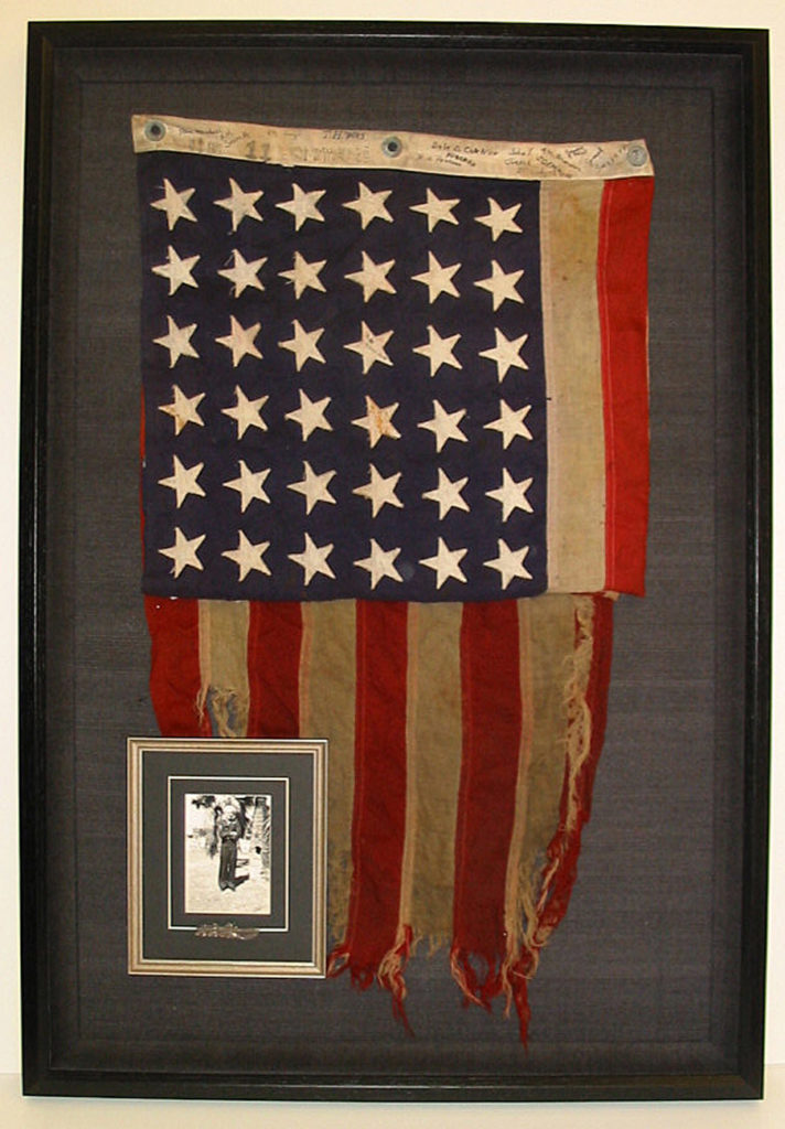 Signed flag shadowbox with small photo and tie clip.